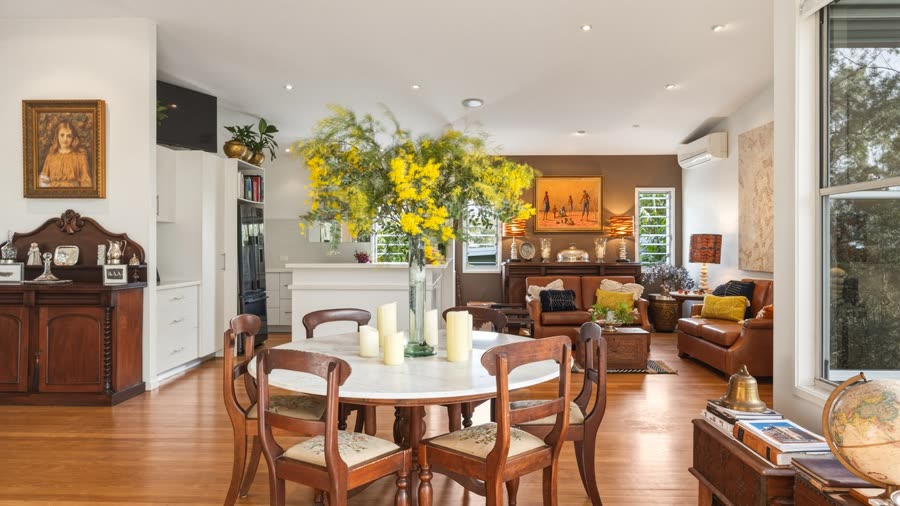 An open-plan dining and living area with a round wooden table